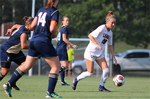 Women's soccer player runs upfield with control of the ball