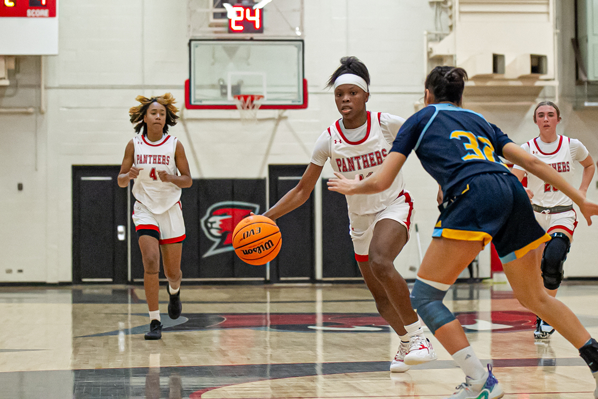 Woman dribbles basketball on court