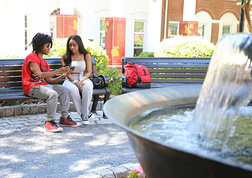 {two students sit on a bench at the Glover Garden}