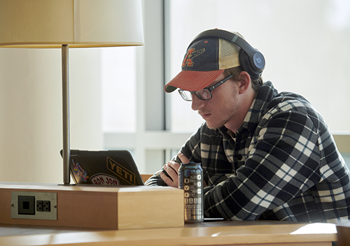 A seated male student works at a laptop