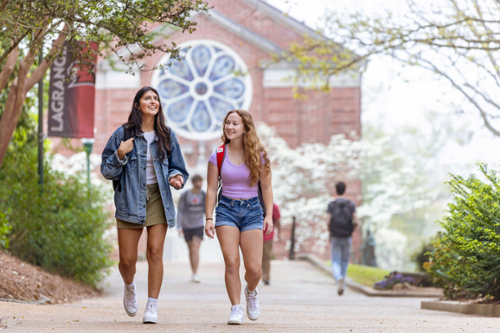 Two female students walk toward the camera on a sunny day